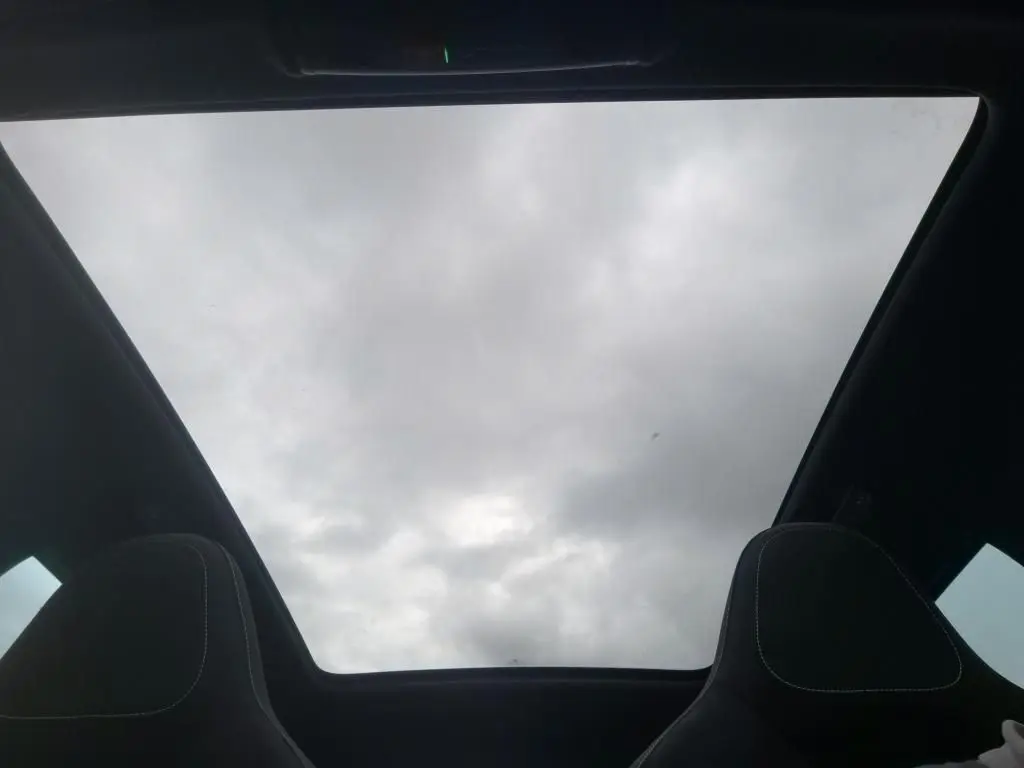 Vue intérieure du toit panoramique du Skoda Kamiq 2024 gris foncé, avec sièges avant en tissu noir visibles en partie.