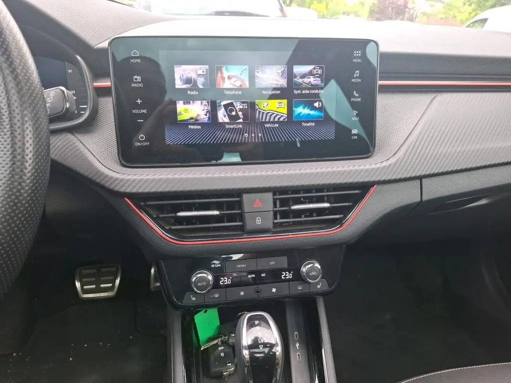 Vue intérieure centrée sur la console centrale du Skoda Kamiq gris foncé, avec écran tactile et commandes climatisation visibles.