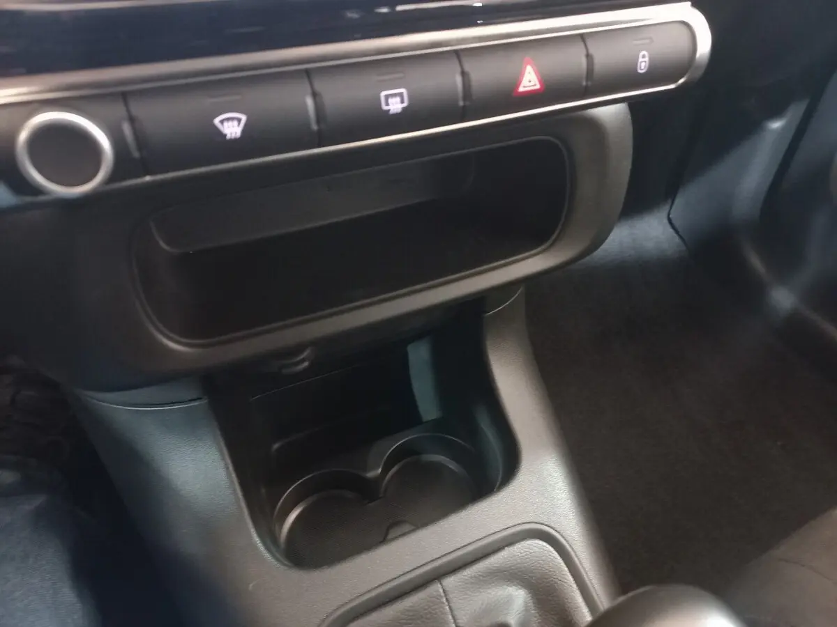 Vue rapprochée de la console centrale noire de la Citroën C3 2024, avec porte-gobelets et boutons de commande alignés.