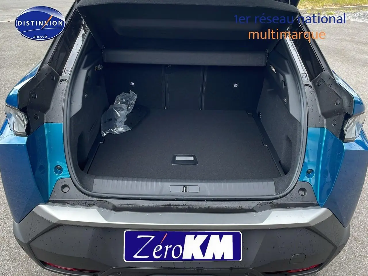 Coffre ouvert en vue arrière d'un Peugeot 3008 Hybrid 145 GT e-EAT8 bleu obsession avec hayon motorisé visible.