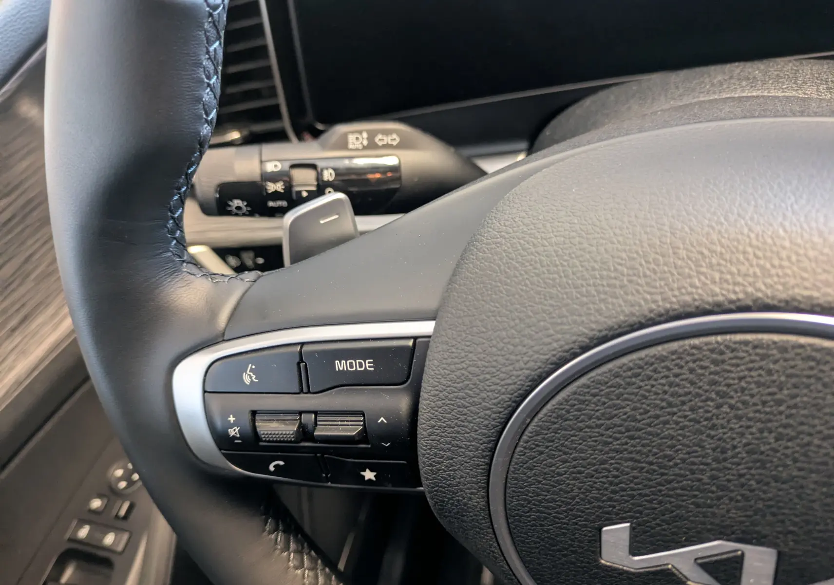 Gros plan sur le volant cuir noir du Kia Sportage 2025, avec commandes intégrées et palettes au volant visibles.