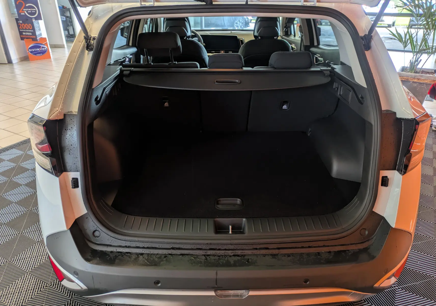 Coffre ouvert vu de l'arrière d'un KIA SPORTAGE blanc 2025, montrant l'espace de chargement et l'intérieur noir.