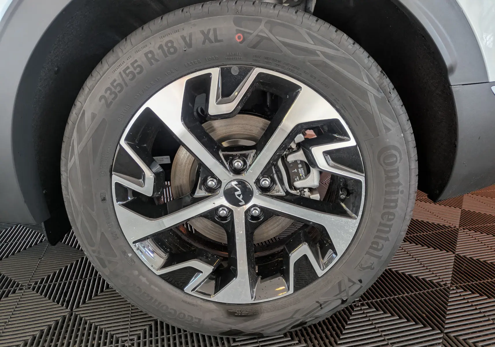 Gros plan sur la jante alliage 18 pouces bicolore du KIA SPORTAGE blanc MY25, avec logo Kia au centre.