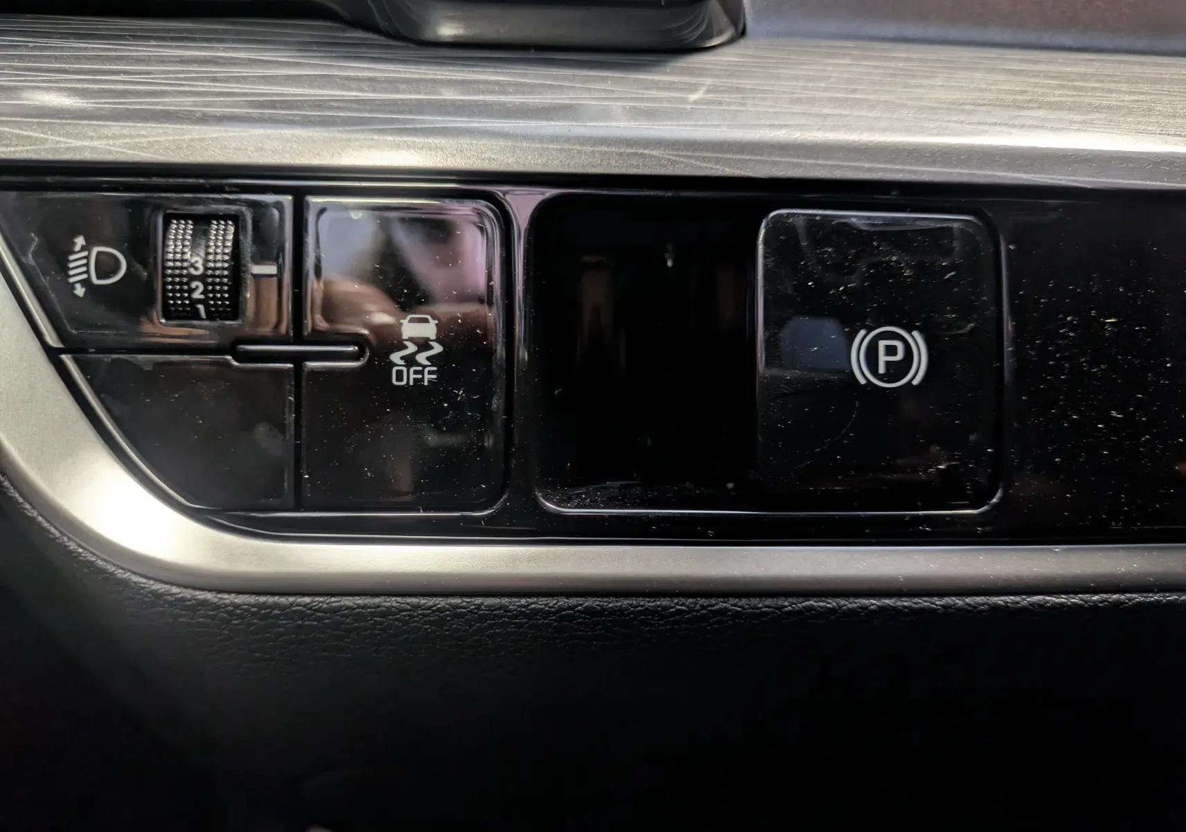 Gros plan sur les commandes noires du tableau de bord du Kia Sportage MY25, boutons ABS et frein de parking électrique.