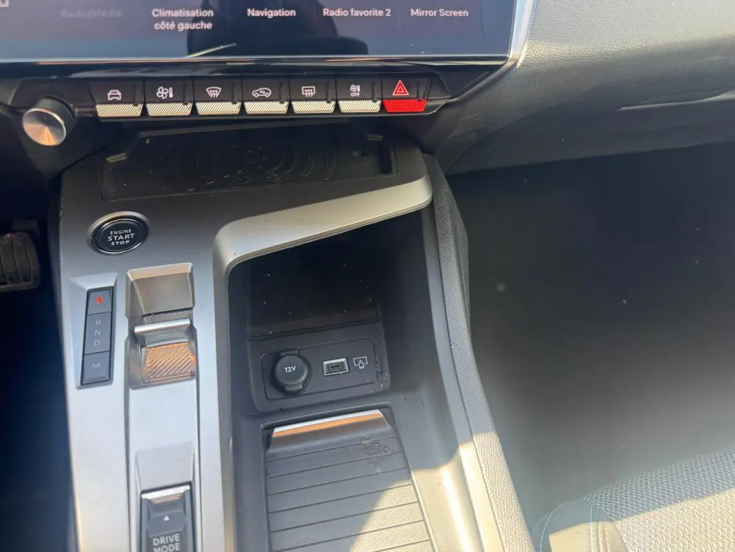 Vue rapprochée de la console centrale grise de la Peugeot 308 Hybrid 136 e-DCS6 Allure avec levier de vitesse automatique et boutons de commande.
