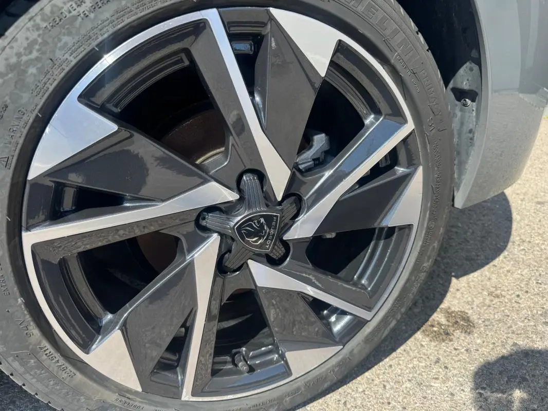Gros plan sur la jante alliage 17 pouces bicolore noir et argentée d'une Peugeot 308 Hybrid 2025 gris.