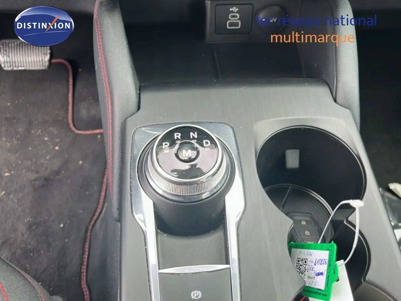 Vue rapprochée de la console centrale du Ford Kuga 2024 bleu chrome, avec molette de boîte auto et porte-gobelets.
