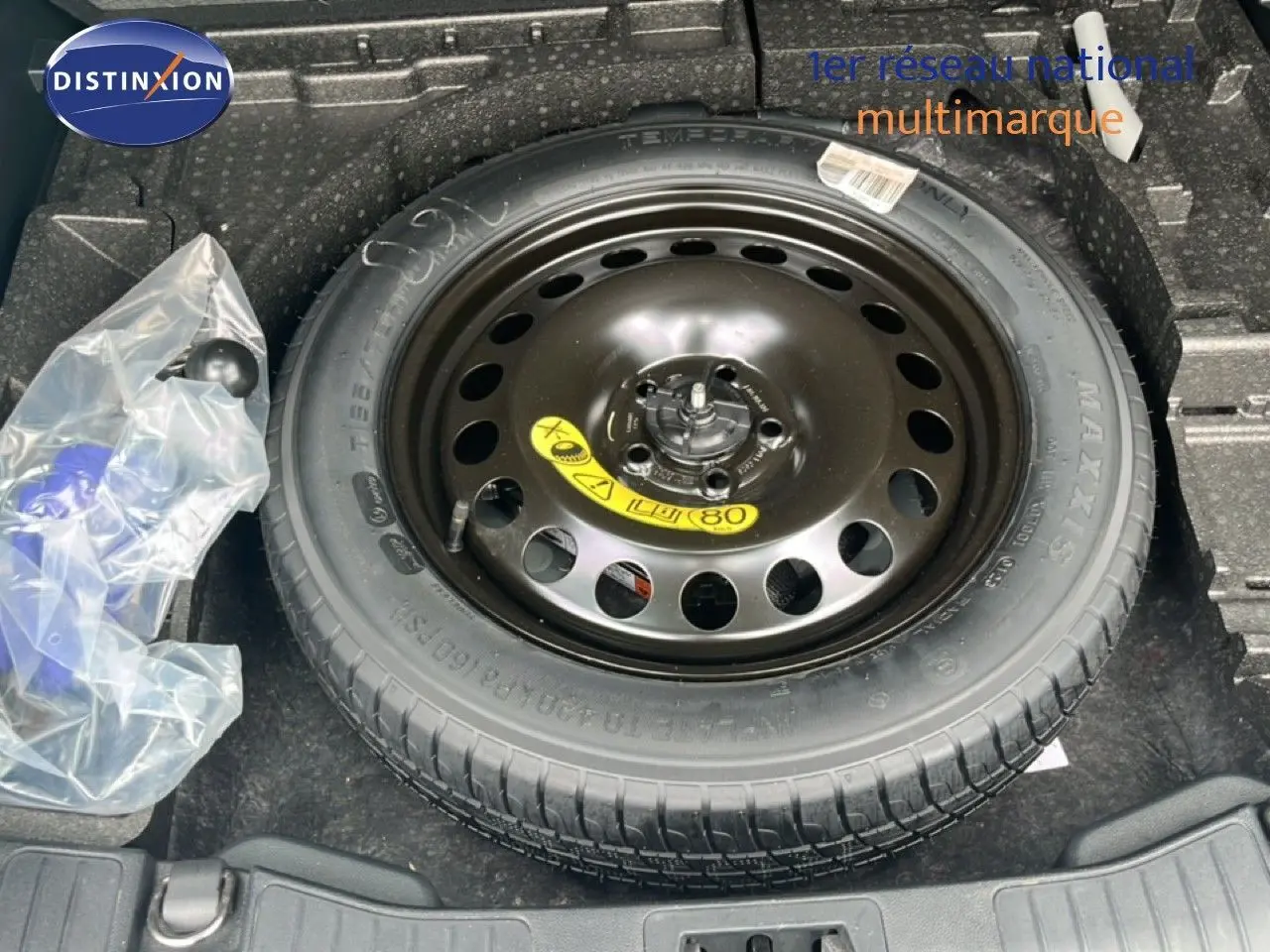 Vue plongeante sur la roue de secours noire dans le coffre d'un Ford Kuga bleu chrome métal 2024.