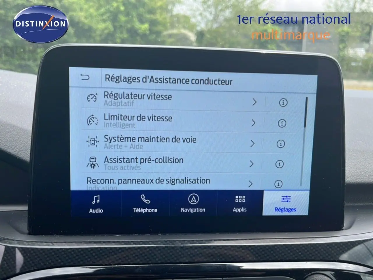 Écran tactile central affichant les réglages d’assistance conducteur dans un Ford Kuga bleu chrome métal, vue intérieure frontale.