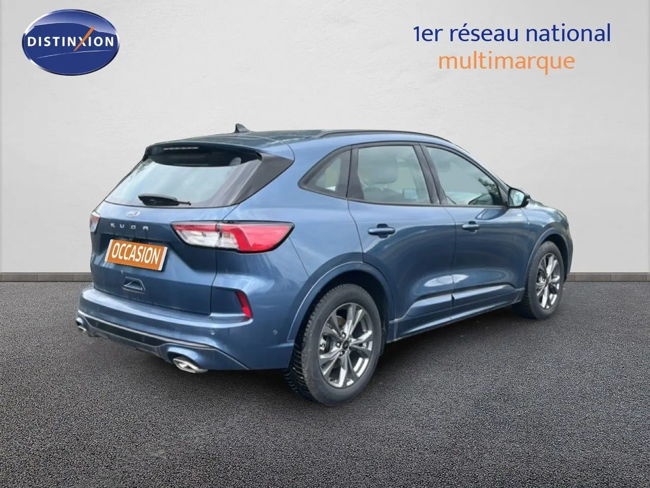 Ford Kuga 2024 bleu chrome métal en vue 3/4 arrière droit, finition ST-LINE avec jantes alliage et double sortie d’échappement.