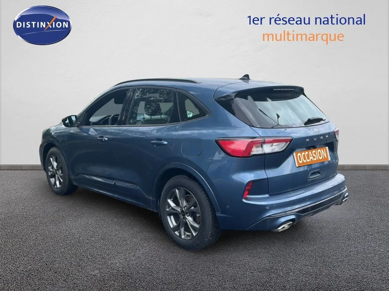 Vue 3/4 arrière droite d'un Ford Kuga 2024 bleu chrome métal avec jantes alliage et double sortie d'échappement.