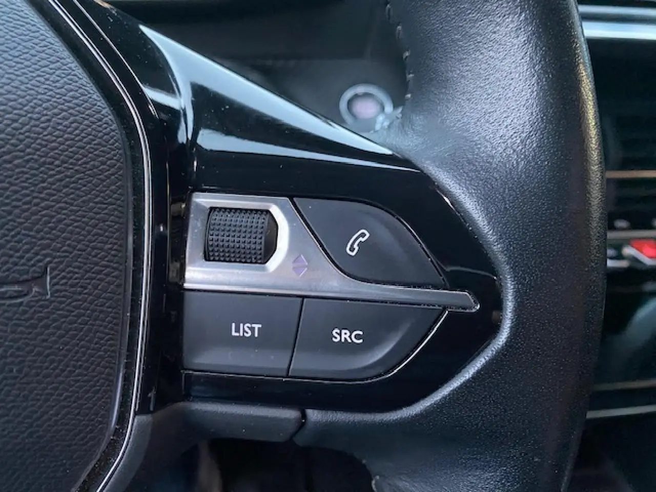 Gros plan sur les commandes gauche du volant en cuir noir du Peugeot 2008 blanc de 2020.