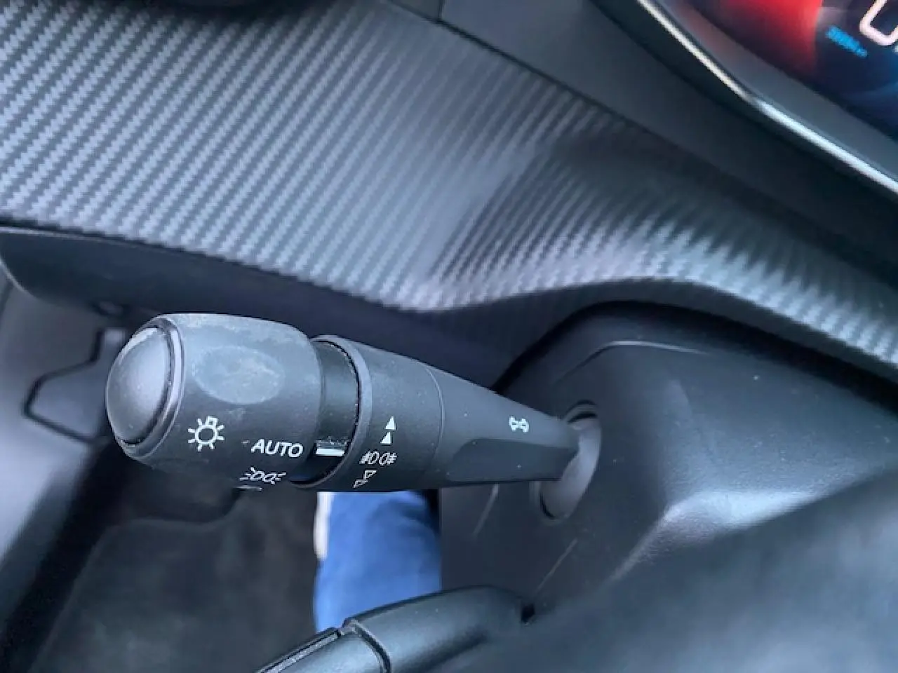 Gros plan sur la manette des feux avec réglage automatique dans l'habitacle du Peugeot 2008 blanc 2020.