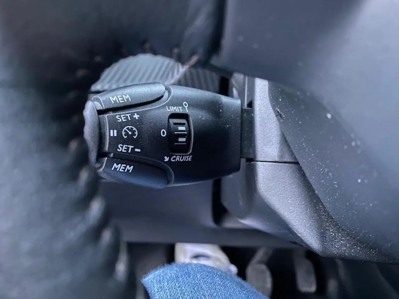 Gros plan sur la commande de régulateur de vitesse au volant d'un Peugeot 2008 blanc de 2020.