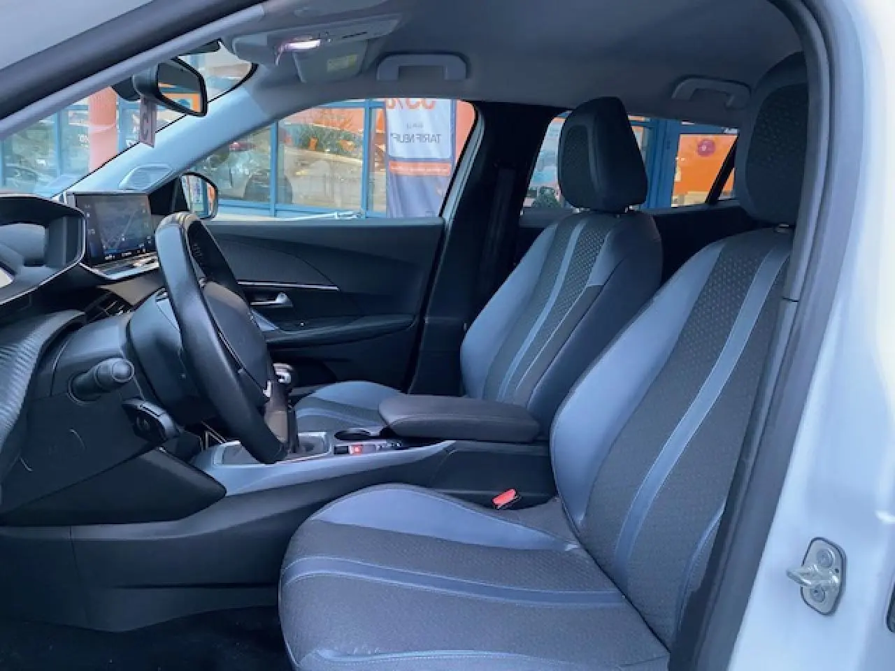 Intérieur avant droit du Peugeot 2008 blanc 2020, sièges tissu gris à surpiqûres bleues et tableau de bord moderne.