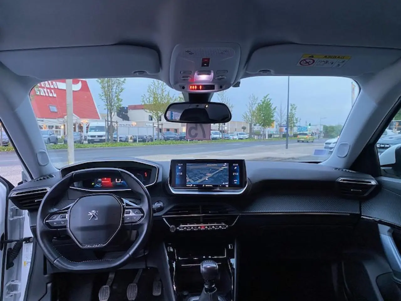 Vue intérieure avant du Peugeot 2008 blanc de 2020, avec tableau de bord moderne et écran tactile de navigation.