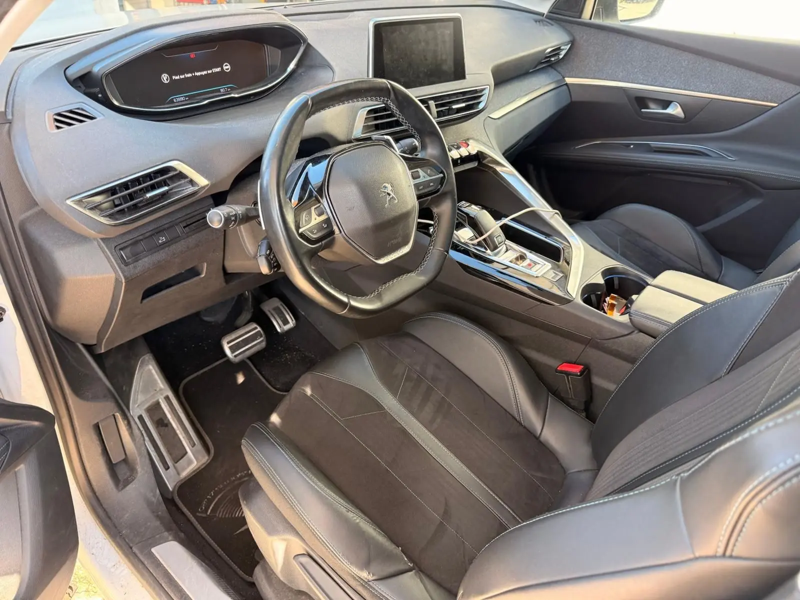 Intérieur du Peugeot 3008 2019 en cuir noir, vue côté conducteur montrant le tableau de bord et la console centrale moderne.