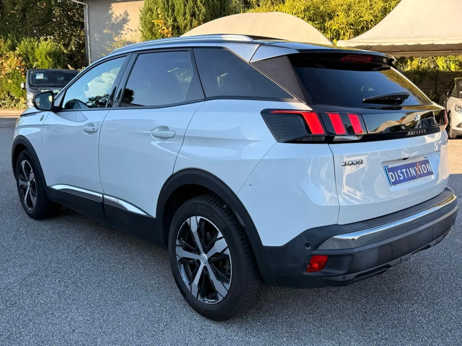 Peugeot 3008 blanc nacré vue 3/4 arrière droit, avec feux arrière à griffes et jantes alliage noires.