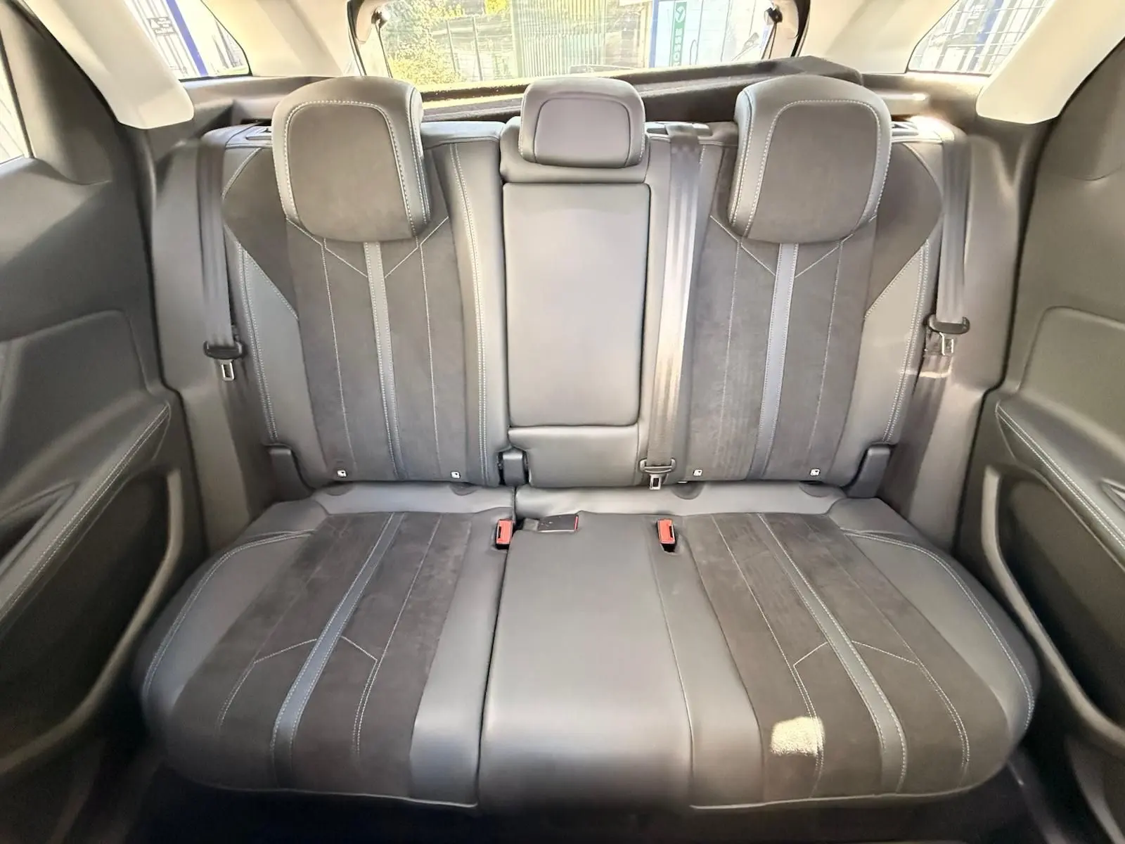 Vue arrière intérieure du Peugeot 3008 blanc nacré, montrant la banquette arrière en cuir et alcantara avec appuie-têtes intégrés.