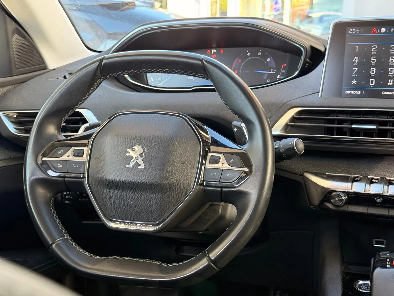 Vue intérieure centrée sur le volant cuir noir du Peugeot 3008 avec tableau de bord et écran tactile visible.