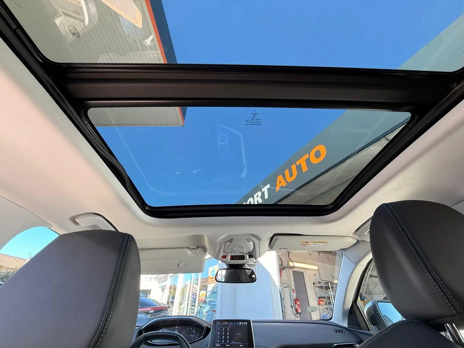 Vue intérieure du Peugeot 3008 blanc nacré de 2019, mettant en valeur le toit panoramique et le tableau de bord moderne.