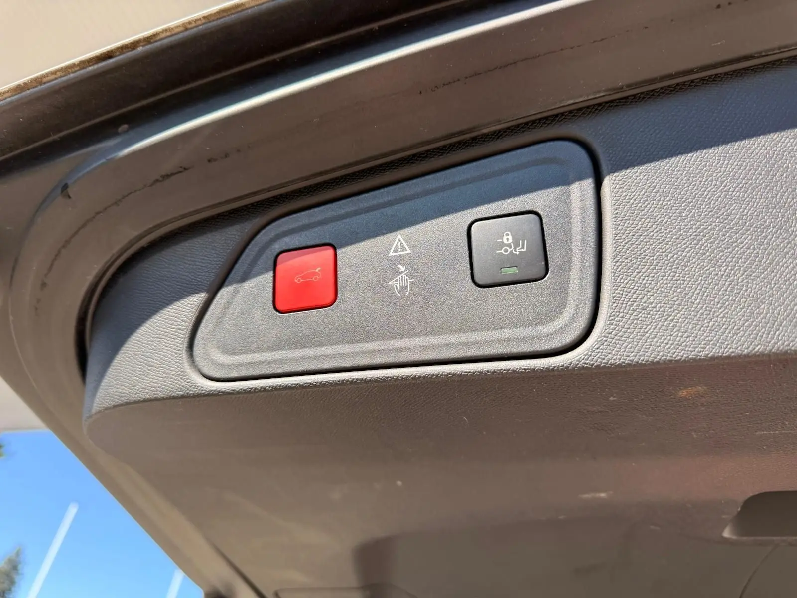 Gros plan sur les boutons d'ouverture et de verrouillage électrique du hayon du Peugeot 3008 blanc nacré, vue intérieure arrière.