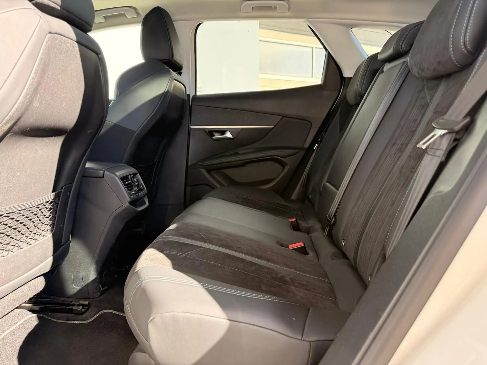Vue latérale droite de l'intérieur arrière d'un Peugeot 3008 blanc nacré, sièges en cuir et alcantara noirs.