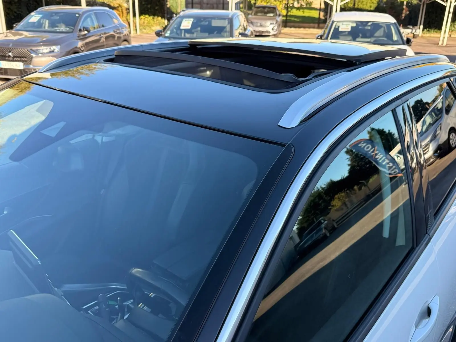 Vue rapprochée du toit ouvrant panoramique et du côté droit du Peugeot 3008 blanc nacré stationné en extérieur.