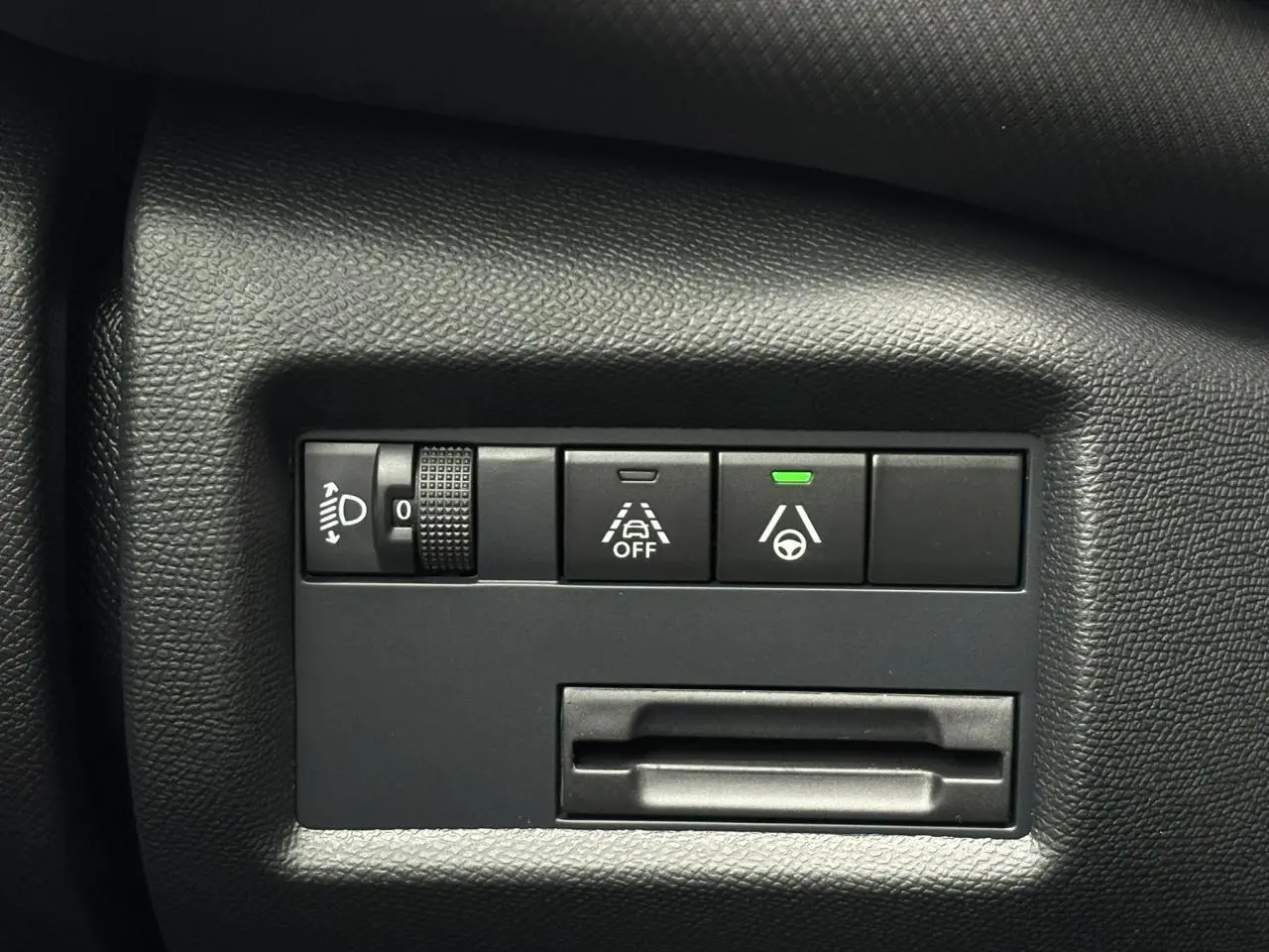 Gros plan sur les commandes d’aide à la conduite et réglage des phares du tableau de bord noir du Citroën C5 Aircross Hybrid.