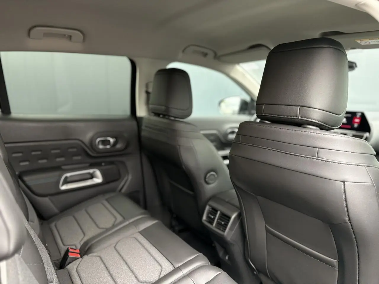 Vue intérieure arrière montrant les sièges en cuir noir du Citroën C5 Aircross Hybrid 2025 avec appuis-tête avant.