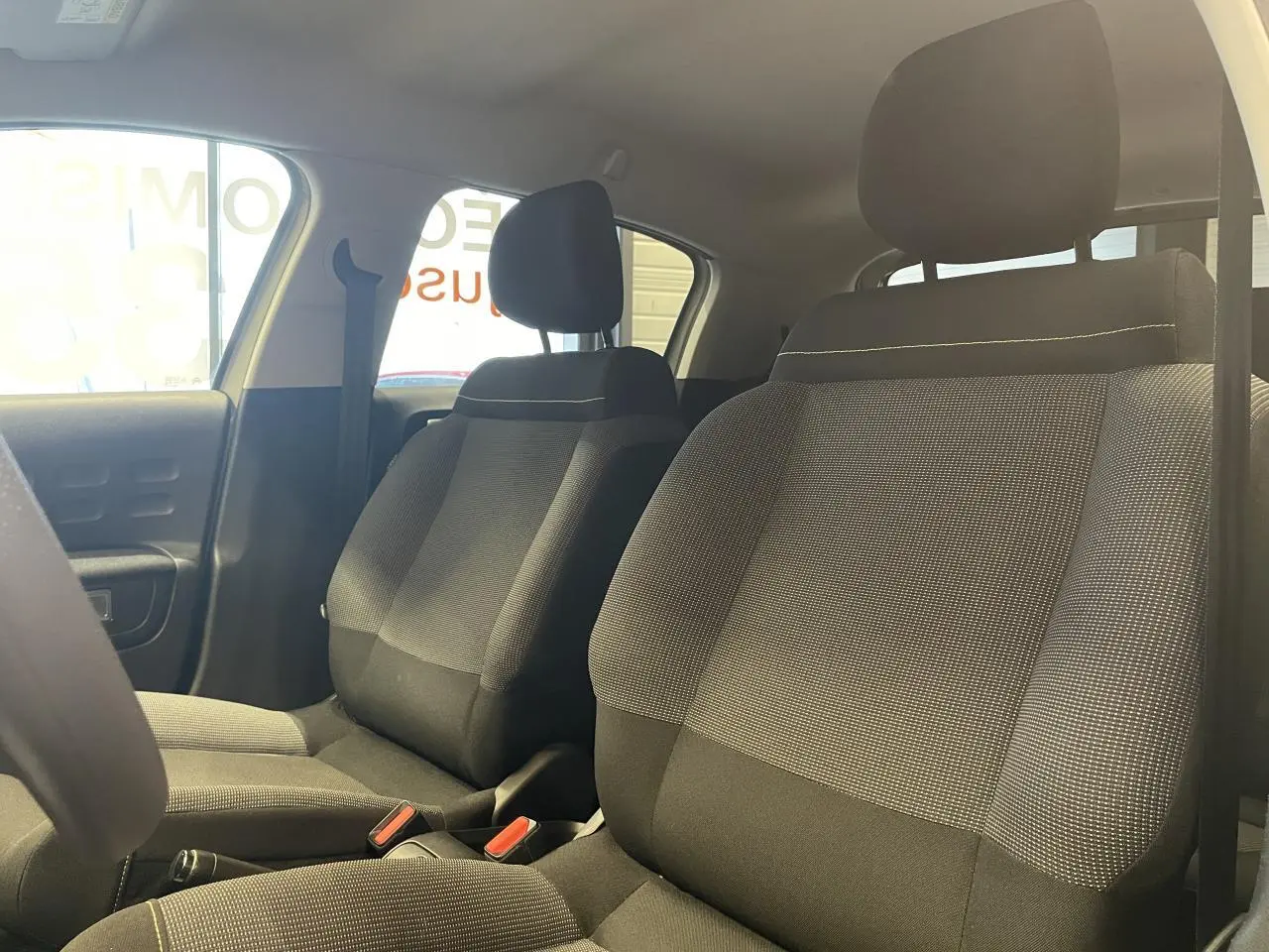 Vue intérieure des sièges avant en tissu gris avec surpiqûres jaunes de la Citroën C3 2024.