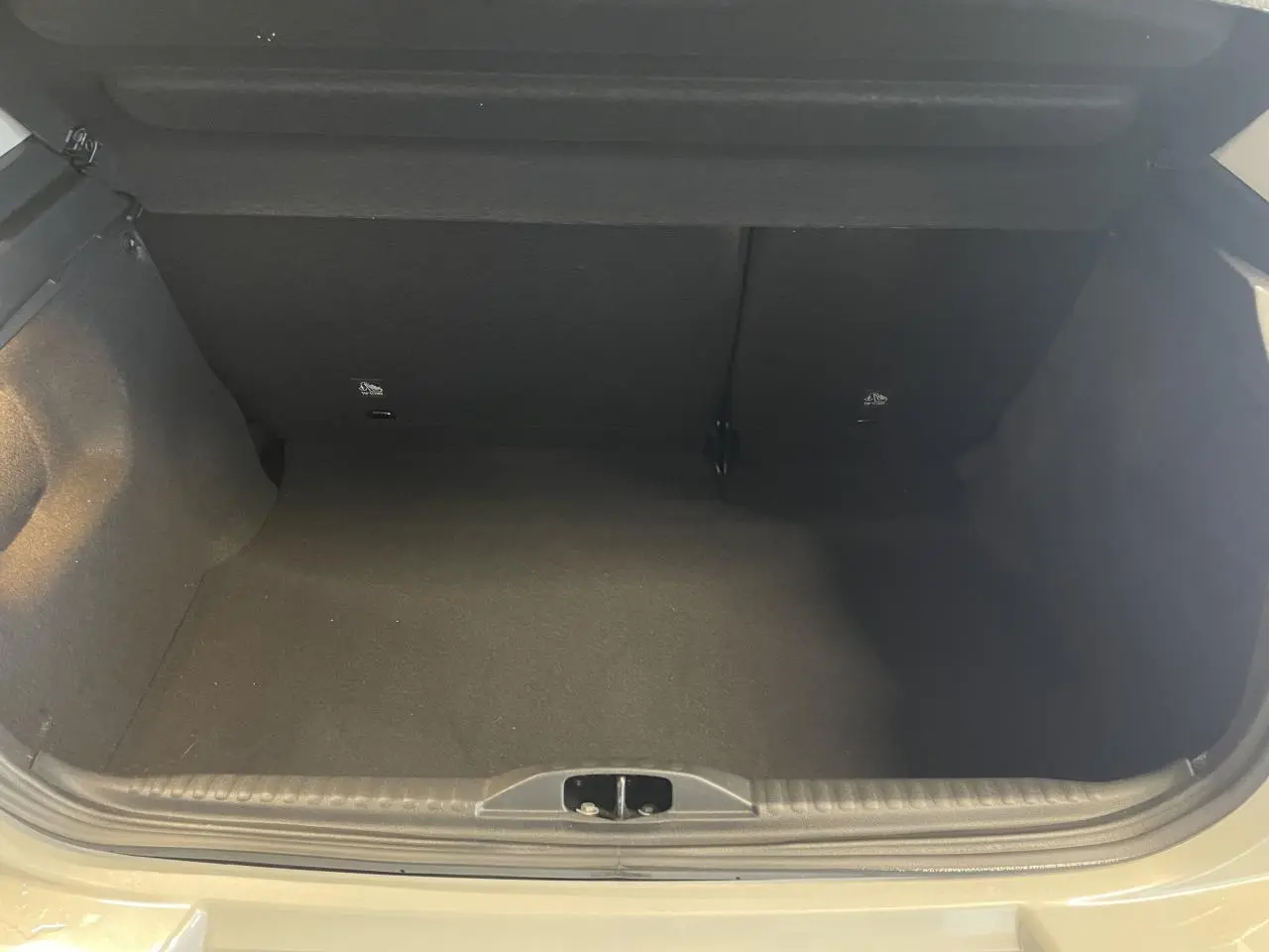 Coffre ouvert vu de face d'une Citroën C3 beige clair 2024, espace de rangement vide et propre.
