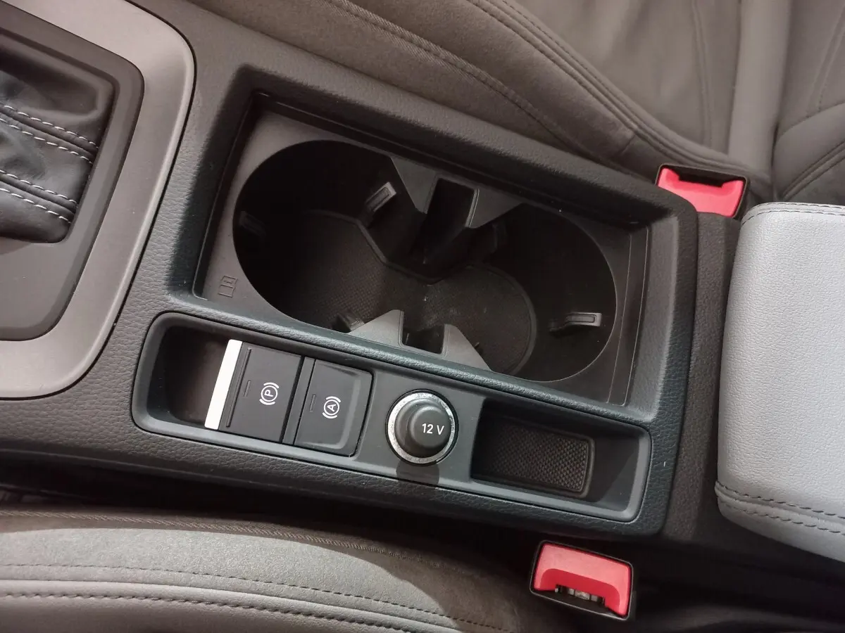 Gros plan sur la console centrale noire avec porte-gobelets et commandes 12V de l'Audi Q3 blanc 45 TFSI E S Line.