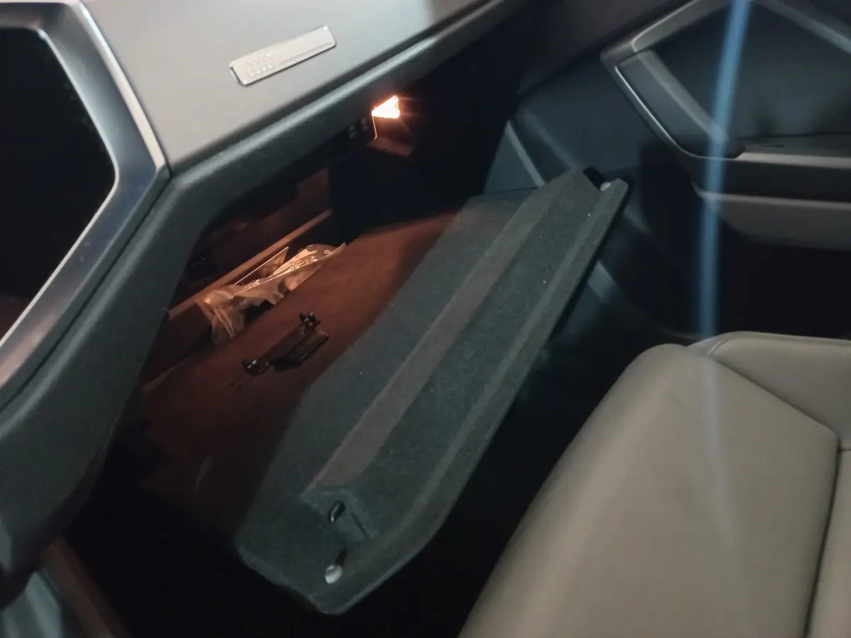 Gros plan sur la boîte à gants ouverte côté passager de l'Audi Q3 45 TFSI e 2021, intérieur noir et siège beige.