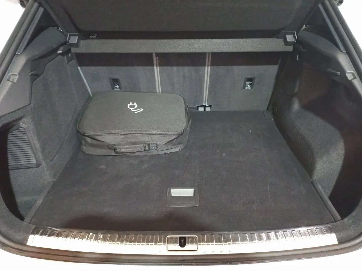 Coffre ouvert vu de face d’un Audi Q3 blanc hybride rechargeable, avec sac de charge noir posé à gauche.