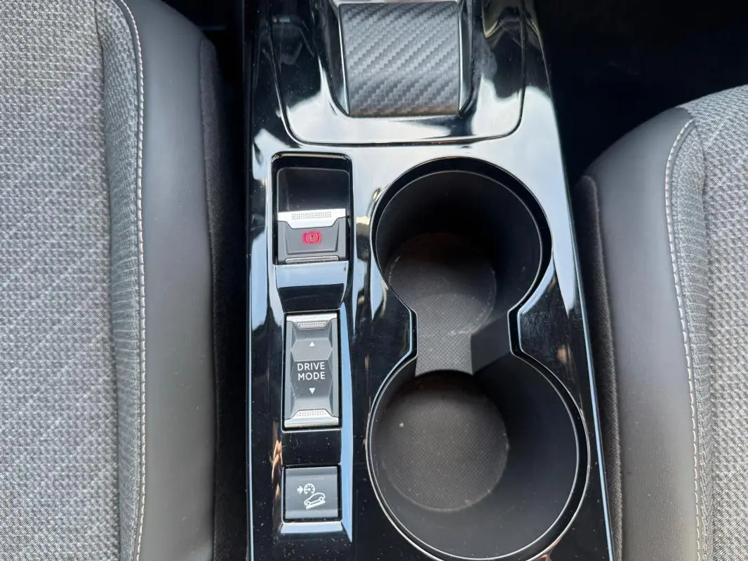 Vue plongeante sur la console centrale noire du Peugeot 2008 Hybrid 136 e-DCS6 Allure avec boutons Drive Mode et frein à main électrique.