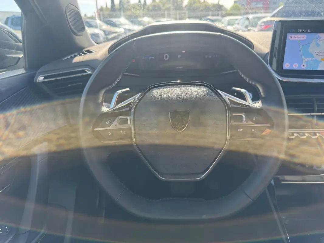 Vue rapprochée du volant noir du Peugeot 2008 Hybrid 136 e-DCS6 Allure avec écran tactile et cockpit numérique visible.