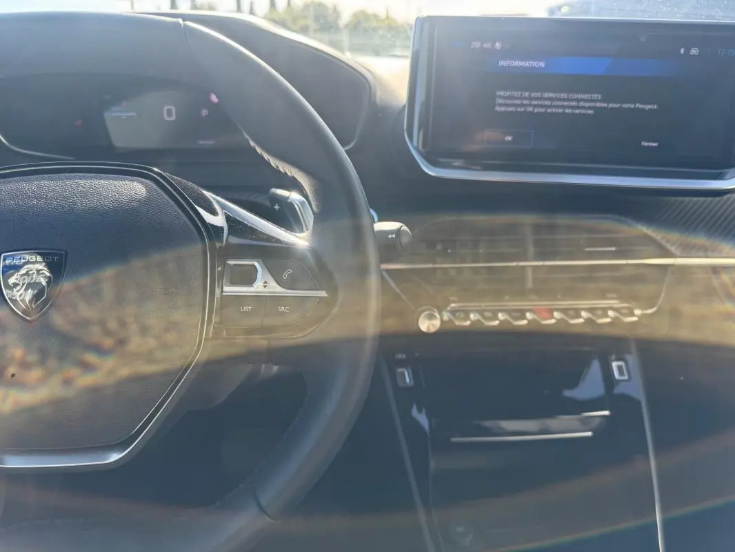 Intérieur du Peugeot 2008 Hybrid 136 Allure 2025, vue sur le volant noir et l'écran tactile central avec commandes modernes.