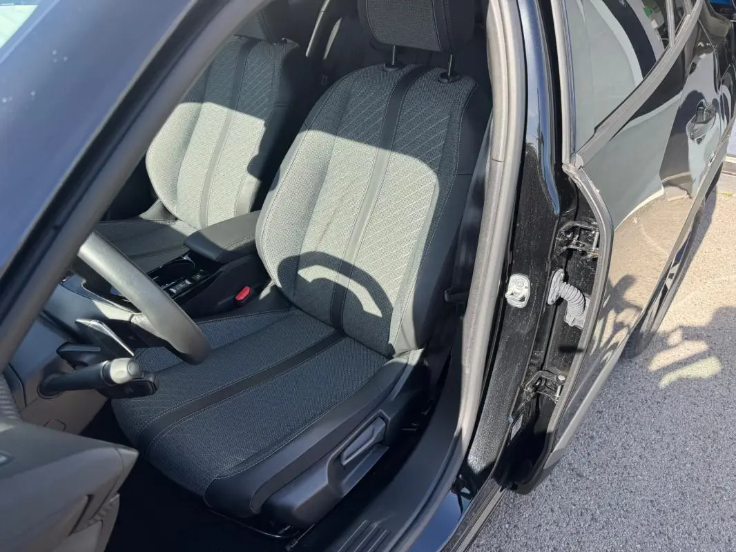Vue intérieure côté conducteur du Peugeot 2008 Hybrid noir 2025, mettant en valeur le siège avant et la portière ouverte.