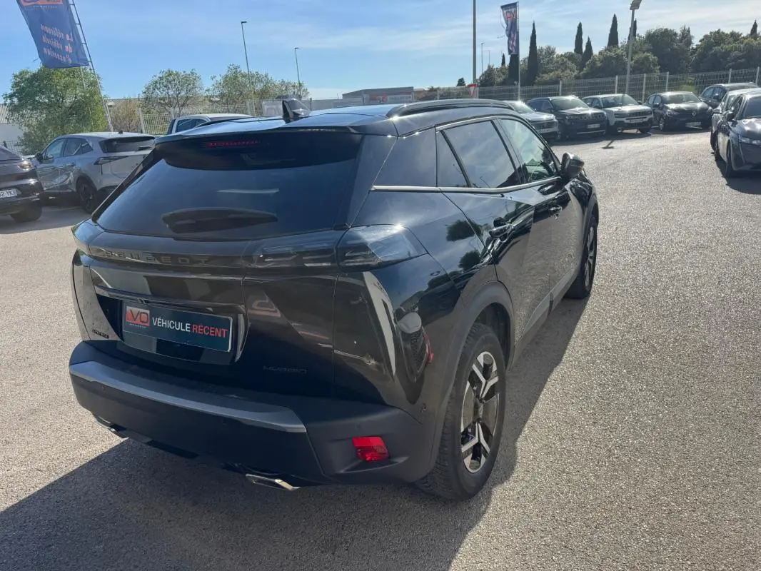 Peugeot 2008 Hybrid noir en 3/4 arrière droit, avec barres de toit et jantes alliage 17 pouces visibles.