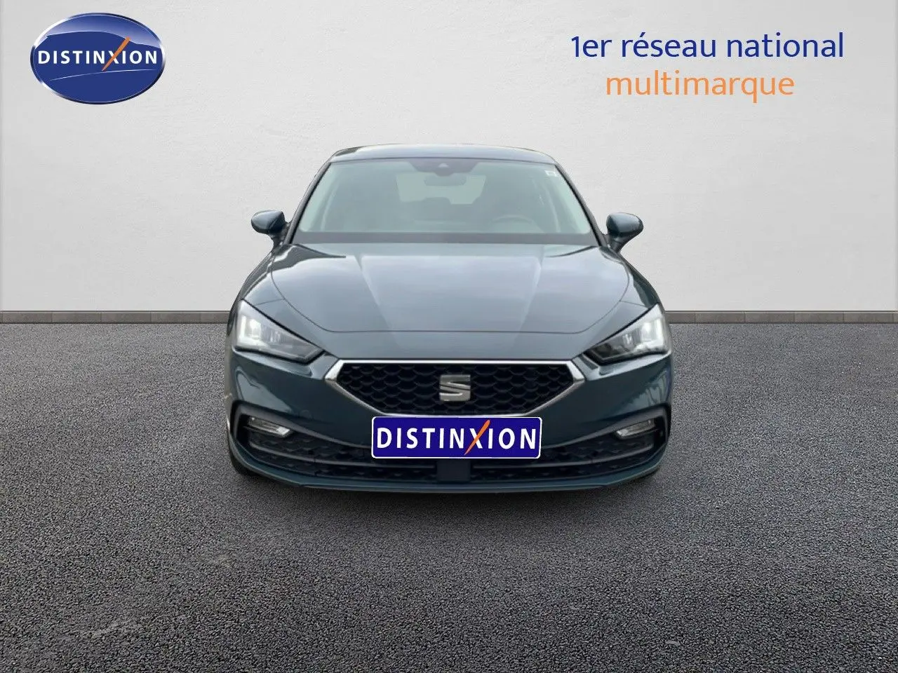 Vue frontale d'une SEAT LEON 2.0 TDI gris magnétique métal avec calandre hexagonale et phares LED allumés.