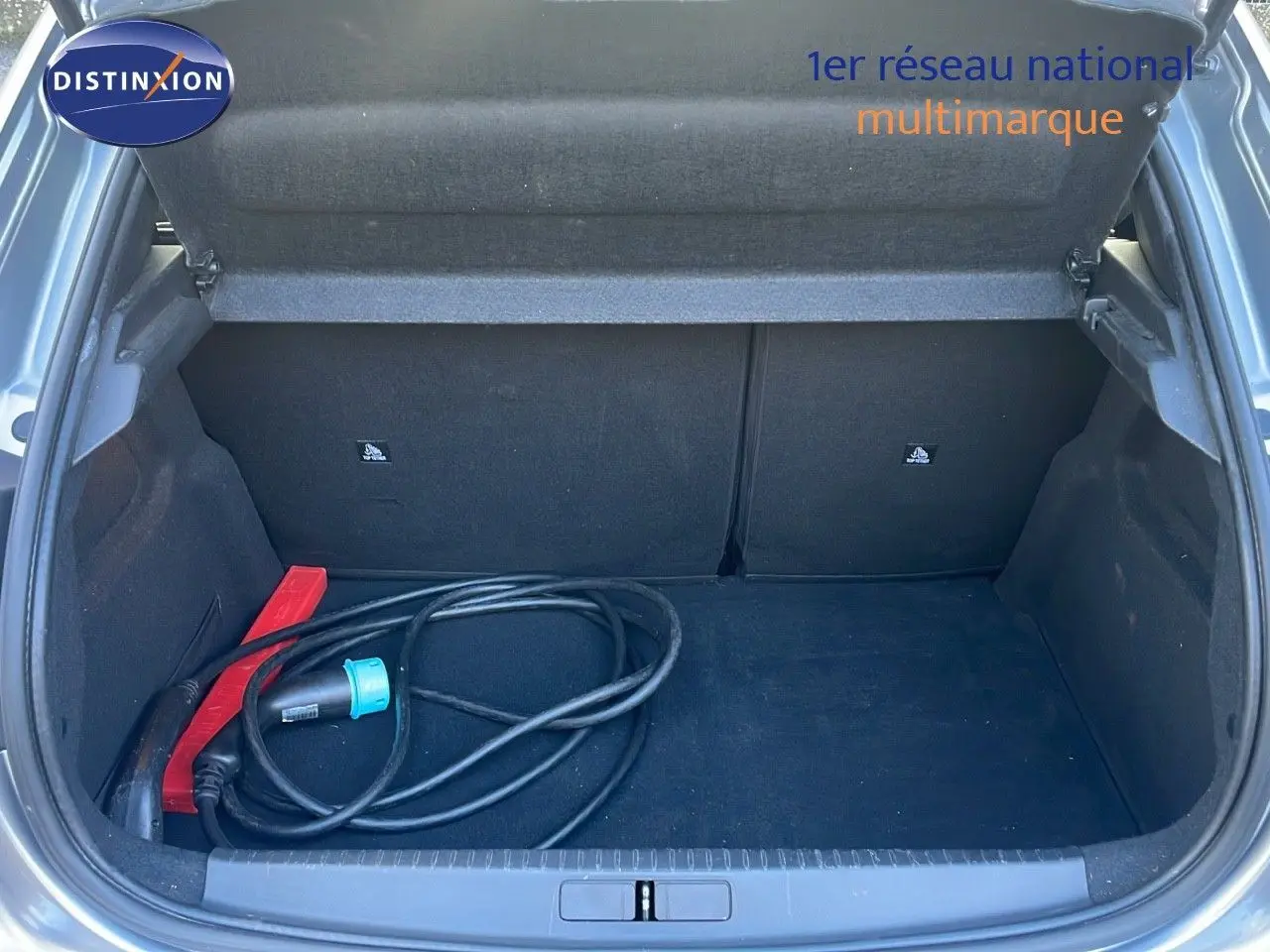 Coffre ouvert d'une Peugeot 208 électrique gris Artense de 2020 avec câble de recharge visible à l'intérieur.
