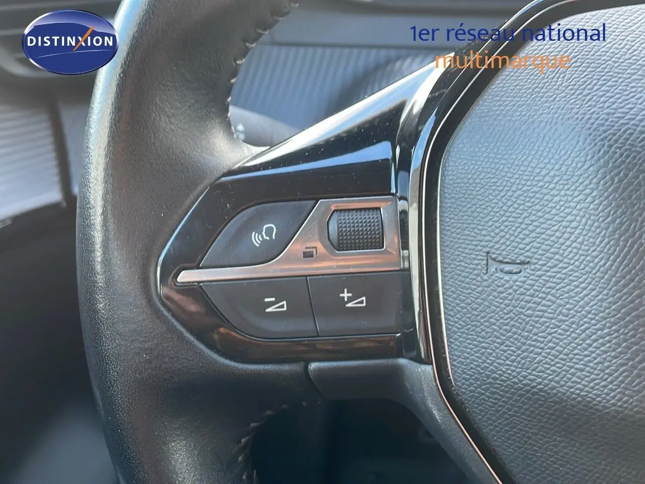 Gros plan sur les commandes au volant côté gauche d'une Peugeot 208 électrique gris Artense de 2020.