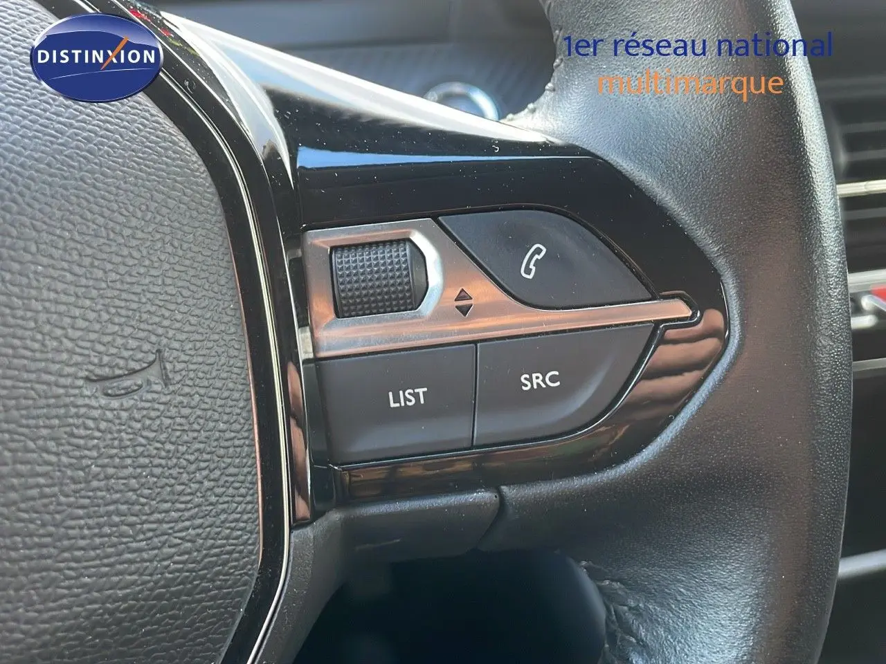 Gros plan sur les commandes multifonctions à droite du volant d'une Peugeot 208 électrique gris Artense, version Active Business.