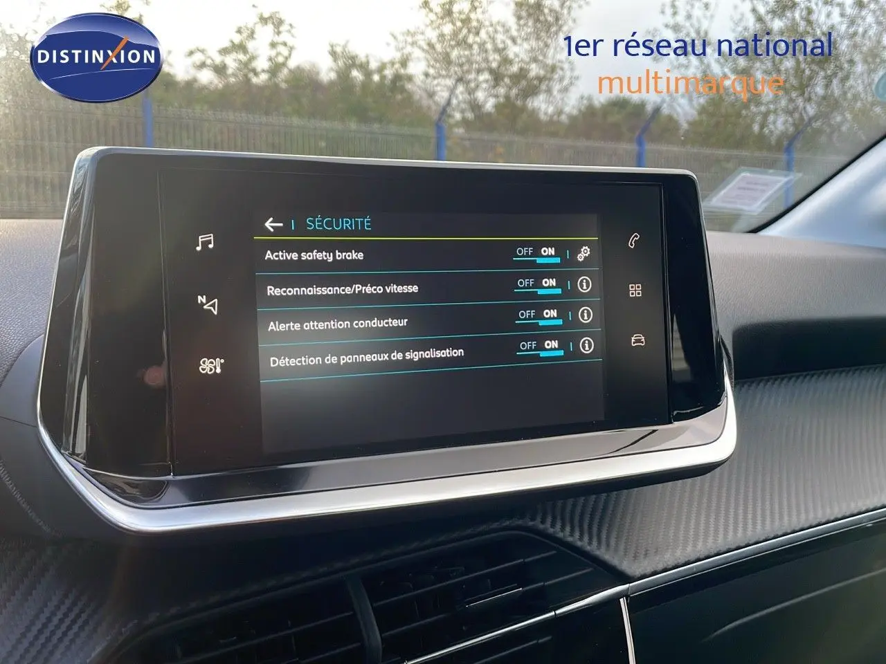 Écran tactile central affichant les options de sécurité dans l'habitacle d'une Peugeot 208 électrique gris Artense.