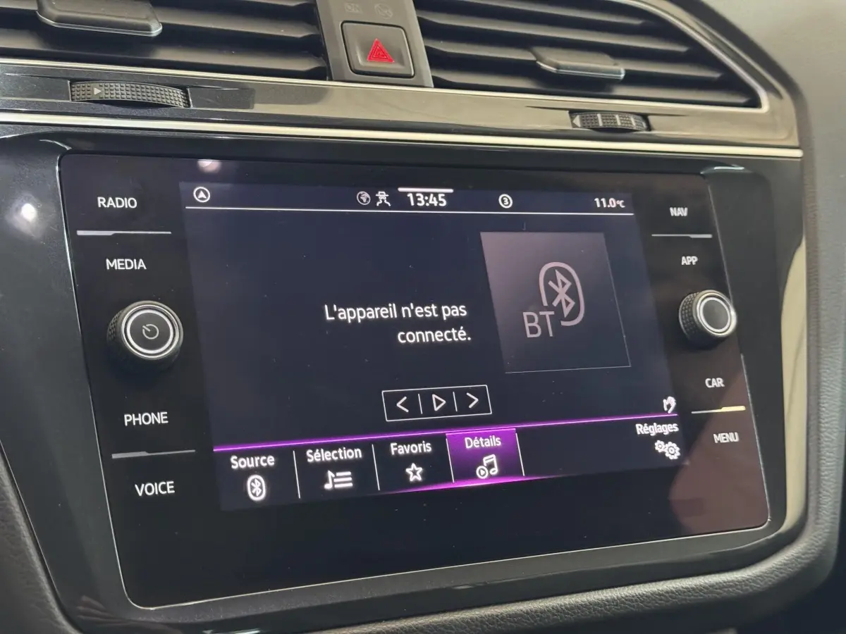 Gros plan sur l'écran tactile central du Volkswagen Tiguan 2021 affichant un message Bluetooth, entouré de commandes noires.