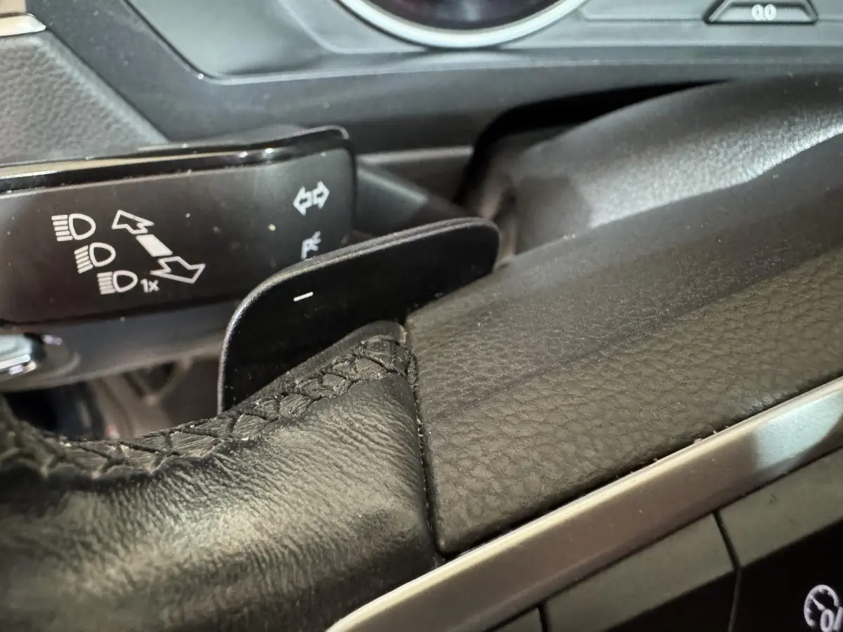 Gros plan sur le levier de vitesse et palettes au volant en cuir noir du Volkswagen Tiguan bleu 2021.