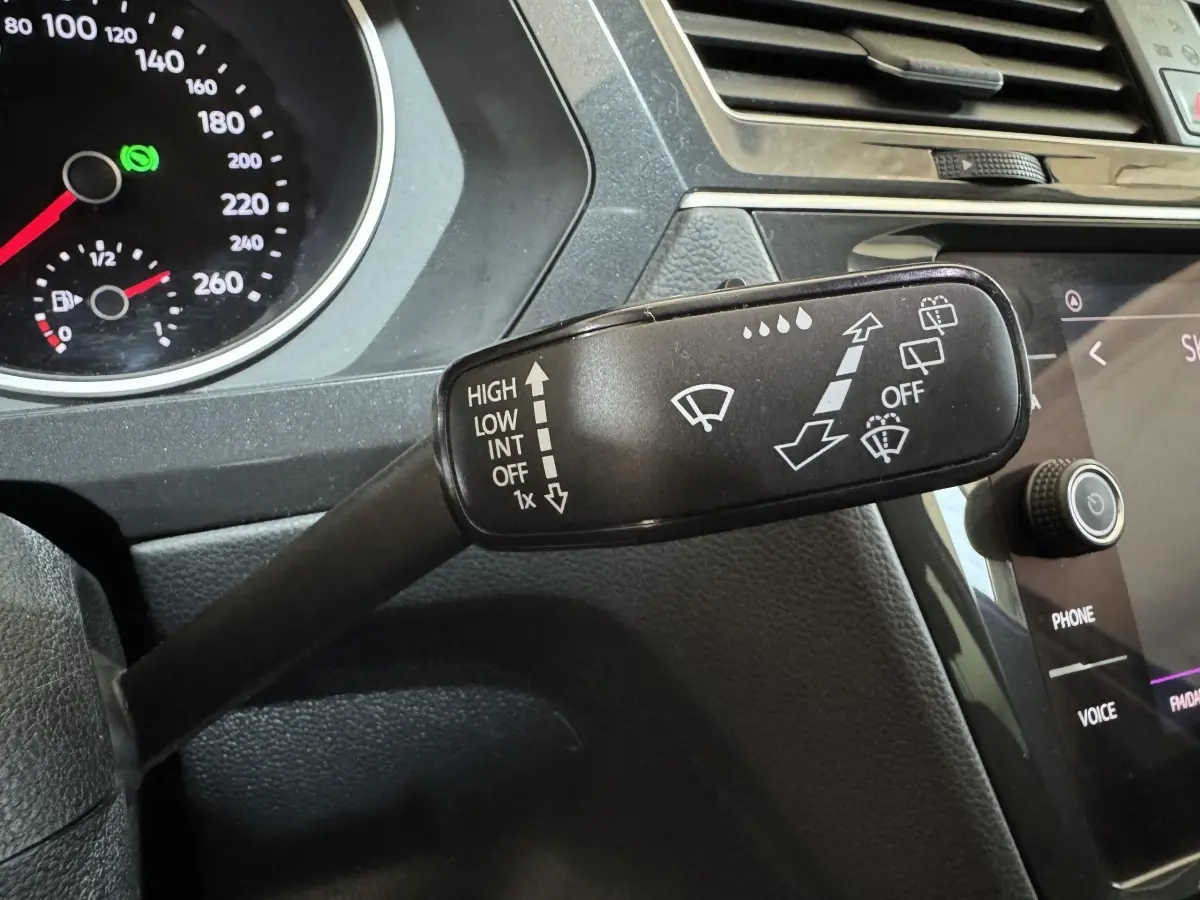 Gros plan sur la commande des essuie-glaces du Volkswagen Tiguan bleu 2021, tableau de bord et écran tactile visibles.