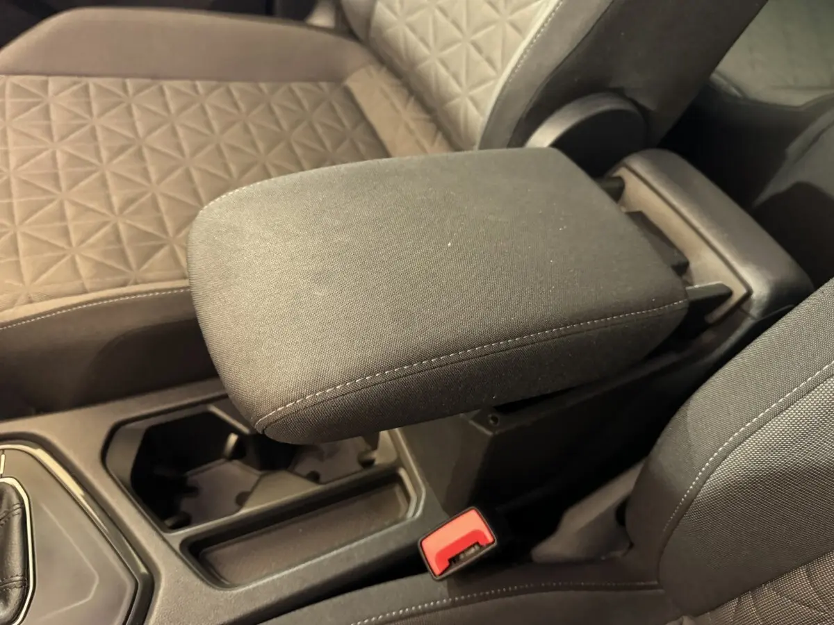 Gros plan sur l'accoudoir central et les sièges avant en tissu gris du Volkswagen Tiguan bleu, version 2021.