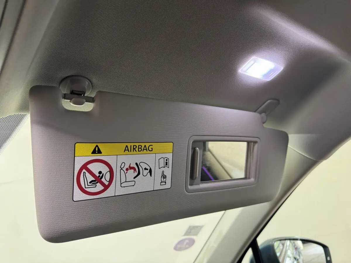 Détail intérieur du pare-soleil côté conducteur avec miroir et avertissement airbag, Volkswagen Tiguan bleu 2021.